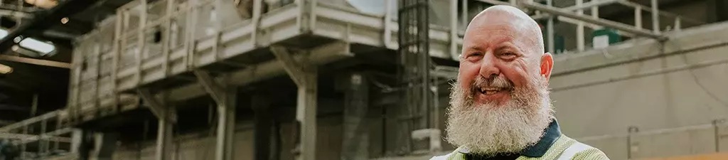 Wellbeing image of man in factory smiling